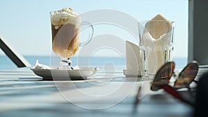 beautiful view of glass with iced coffee with ice cream on background of magnificent view of ocean or sea, concept of