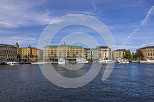 Beautiful view of grand hotel in the center of Stockholm on Baltic coast with ships moored to pier.