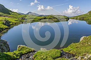 Beautiful view of high mountain lake with sky mirrored in water.