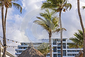 Beautiful view of hotel building with palm trees against a blue sky with white clouds.