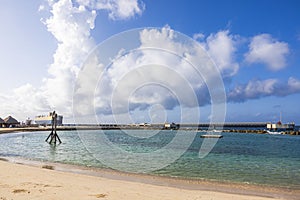 Beautiful view of the hotel\'s sandy beach in the Caribbean Sea with a ship pier in the distance.