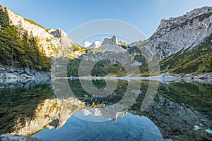 Beautiful view of idyllic colorful autumn scenery with Dachstein mountain summit reflecting in crystal clear Gosausee mountain