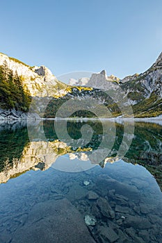 Beautiful view of idyllic colorful autumn scenery with Dachstein mountain summit reflecting in crystal clear Gosausee mountain