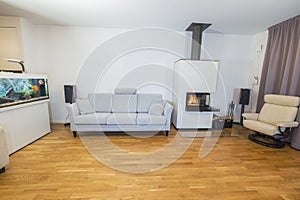 Beautiful view of interior of modern living room. White fireplace, big aquarium with colorful fishes.