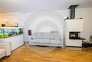 Beautiful view of interior of modern living room. White fireplace, big aquarium with colorful fishes.