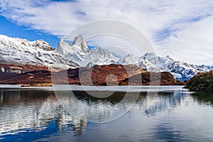 Beautiful view of lake Capri with Fitz roy mountains with white snow peak and colorful red leaves tree in sunny blue sky day in