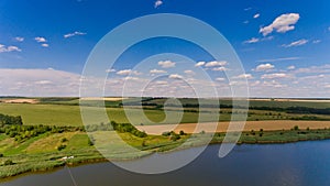 Beautiful view of the lake, green fields and sky with clouds.