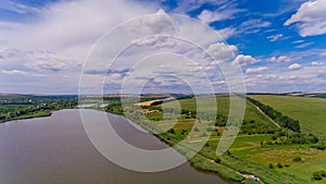 Beautiful view of the lake, green fields and sky with clouds.