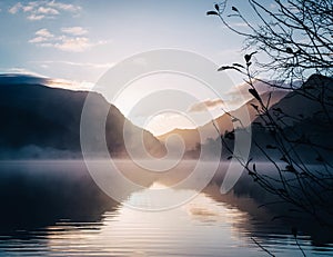 Beautiful view of a lake surrounded by mountains with a glowing sun in the background