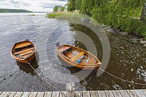 Beautiful view of lake with two boats parked in shore on water background.