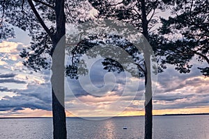 A beautiful view of a large calm lake with a muffled pink light of the evening summer sky with blue atmospheric clouds