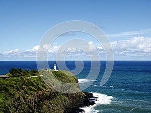 Beautiful view of a lighthouse on a grass covered cliff over the ocean under the cloudy sky