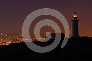 Beautiful view of a lighthouse and a house on a hill captured at night in Cyprus