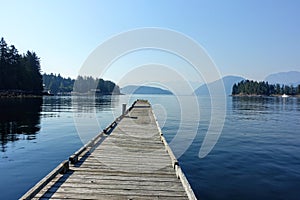 A beautiful view of a long empty dock extending into the ocean waters of the sunshine coast, in Egmont, British Columbia, Canada