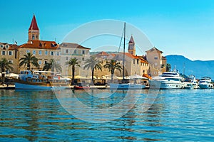 Anchored boats and waterfront promenade with palms in Trogir, Croatia