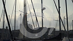 Beautiful view of masts of ships on background of sun and blue sky. Action. Masts of yachts are illuminated by warm