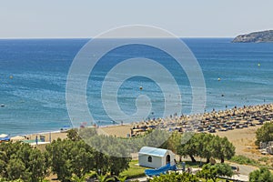 Beautiful view of Mediterranean sea sand beach with sunbeds and sun umbrellas on background. Rhodes.