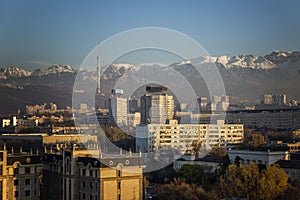 Beautiful view of the modern city against the backdrop of snowy mountains at sunset. Resort, entertainment and industry