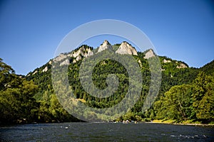 Beautiful view of a mountain and forest with group of people boating on a river