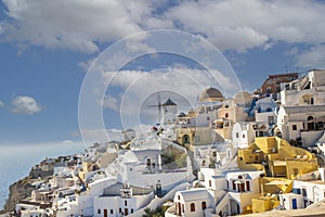 Beautiful view of Oia with traditional white houses and windmills in village, Santorini island, Greece