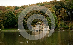 Beautiful view of an old house in the lake with the colorful trees in the background