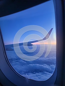 Beautiful view through the open window in airplane on the wing and clouds at sunrise litght