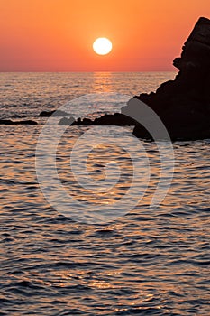 Beautiful view of orange sunset seascape with rocks in Italy. Colorful sunrise landscape