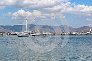 Beautiful View Over the Calm Sea Water Accompanied by Floating Boats Large Mountains with Clear Cloudy Blue Sky Background