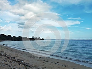 Beautiful View Over the Calm Sea Water During Sunny Weather Accompanied by Large Mountains with Clear Cloudy Blue Sky Background