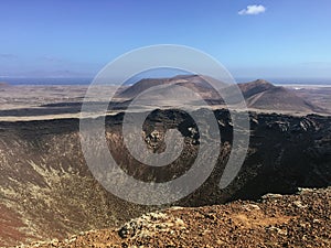 Beautiful view overlooking rusty red desert, distant mountains in Fuerteventura island, Canaries, Spain