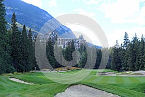 A beautiful view of a par 4 golf hole on a course with a huge mountain in the background, surrounded by forest