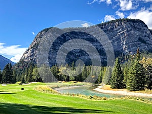 A beautiful view of a par 3 golf hole on a course with mountains in the background photo