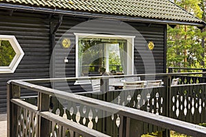 Beautiful view of part facade of typical wooden Swedish house with wooden patio.