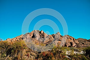 A beautiful view of the red rocky mountain on the contrasting blue sky background.