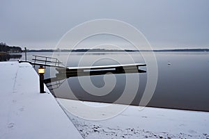 Beautiful view of a reflective lake and a snowy shore on a cloudy day