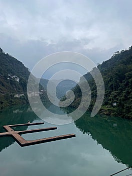 Beautiful view of a reflective river and a kemp dock with forested mountains in a foggy weather photo