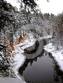 Beautiful view of the Salaca river with snow-covered trees and sandstone cliffs photo