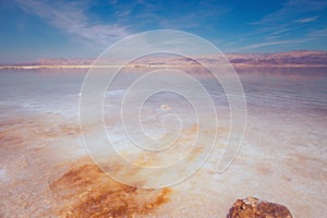 Beautiful view of salty Dead Sea shore with clear water and blue sky. Ein Bokek, Israel