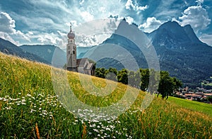 Beautiful view of San Valentino Church in Castelrotto village. Idyllic alpine mountain scenery with fresh green grass on meadows