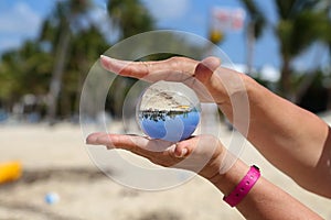 Beautiful view of sandy beach and blue sky through a transparent crystal ball