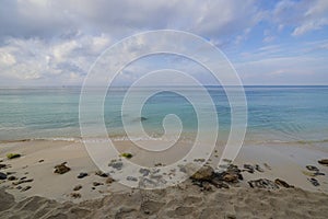 Beautiful view of sandy coastline beach and calm turquoise water surface of Atlantic Ocean merging with blue sky on horizon.