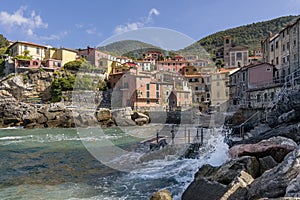 Beautiful view of the seaside village of Tellaro on a sunny day, La Spezia, Liguria, Italy, with the waves crashing on the rocks