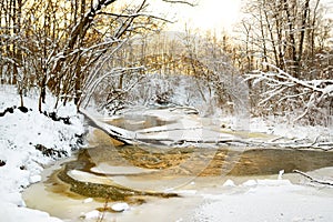 Beautiful view of snow covered forest. Narrow river flowing between snow covered trees. Scenic winter landscape near Vilnius,