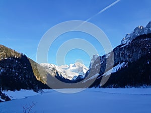 Beautiful view at the snowy mountains and frozen lake at the Gosausee, Austria.