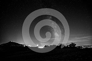 Beautiful view of starred night sky with milky way over a cultivated field Assisi town Umbria, italy in the background