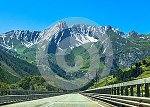 Beautiful view of a straight paved road winding through a forested mountain range in Switzerland