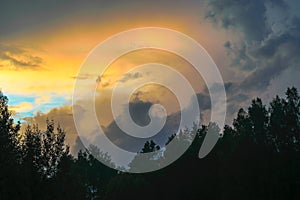 Beautiful view of sunset storm cloud formation enlightened with last yellow sunbeams and visible blue sky