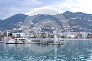 Beautiful view on a town, mountains, sea, lighthouse and ships in Alanya port, Turkey