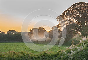 Beautiful view of a tractor cultivating field during sunset