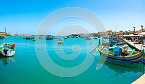 Beautiful view on the traditional eyed colorful boats Luzzu in the Harbor of Mediterranean fishing village Marsaxlokk, Malta